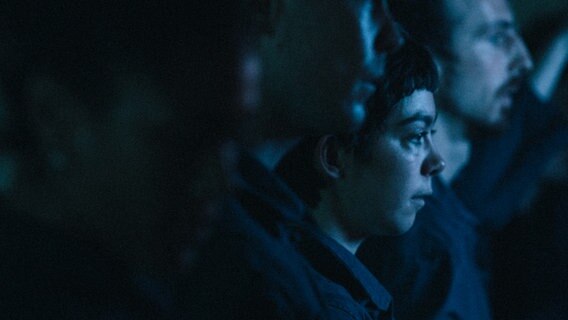 Bei schwachem, blauen Licht sieht man eine Frau und dahinter einen Mann im Profil © Ghislain Mirat 
