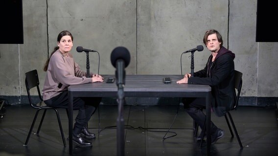 Die Darsteller Julia Wieninger und Lars Rudolph sitzen sich auf einer Bühne an einem Tisch gegenüber. © Thomas Aurin Foto: Thomas Aurin