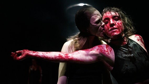 Eine Darstellerin in "Die Räuber" leckt eine andere Darstellerin, die mit Blut überströmt ist, das Gesicht ab. © Armin Smailovic Foto: Armin Smailovic