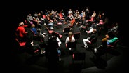 Personen sitzen auf im Kreis angeordneten Stühlen auf einer Bühne © Thomas Aurin / Deutsches Schauspielhaus Hamburg Foto: Thomas Aurin