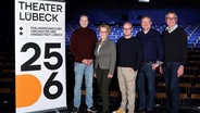 Stefan Vladar, Monika Frank, Malte C. Lachmann, Peter Petereit und Caspar Sawade posieren neben einem Plakat des Theaters Lübeck. © Theater Lübeck Foto: Lutz Roeßler