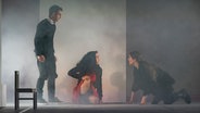 Zwei Frauen sitzen auf dem Boden und schauen sich an, ein Mann steht daneben © Theater Lüneburg / Jochen Quast Foto: Jochen Quast