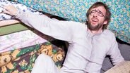 Holger Dexne liegt vor Blümchenmustern am Boden beim Stück "Buten vör de Döör" am Ohnsorg-Theater © Ohnsorg Theater /  Sinje Hasheider Foto:  Sinje Hasheider