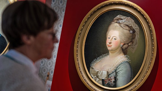 Eine Frau betrachtet ein Gemälde, das Caroline Mathilde (1751-1775), Königin von Dänemark und Norwegen, zeigt, im Residenzmuseum im Celler Schloss. © picture alliance / dpa Foto: Moritz Frankenberg