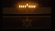 Ein traditioneller jüdischer Leuchter hinter einer verregneten Scheibe. © picture alliance/dpa | Marijan Murat 