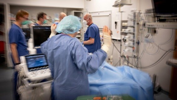 Ein Intensivmediziner hebt die Hände an einem Krankenhaus-Bett stehend. © rbb/DOCDAYS/Carl Gierstorfer 