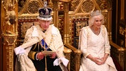 König Charles mit Krone sitzt neben Königin Camilla und liest im November 2023 bei der Regierungserklärung im Oberhaus des britischen Parlaments © dpa Foto: Leon Neal/PA Wire/dpa +++ dpa-Bildfunk +++