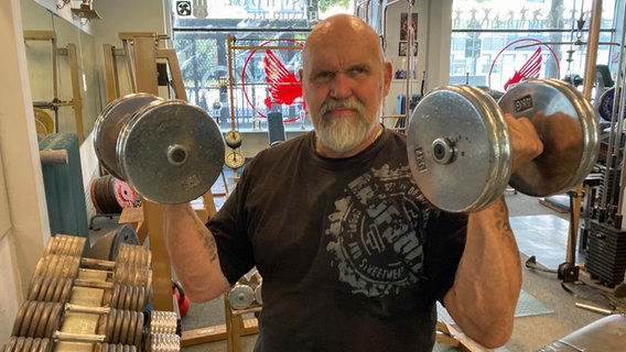 Claus Maibaum, owner of the Olympic Fitness Studio in Hamburg, lifts two dumbbells.  © NDR Photo: Johannes Huhmann