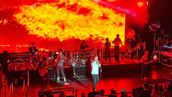 Eine Band spielt auf einer Theaterbühne, im Hintergrund werden Flammen auf eine Leinwand projiziert. Eine Band spielt auf einer Theaterbühne, im Hintergrund werden Flammen auf eine Leinwand projiziert. © NDR Foto: Sabine Hausherr