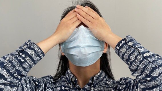 Eine Frau mit Mund- und Nasenschutz schlägt ihre Hände vors Gesicht. © picture alliance / BSIP | IMAGE POINT FR / LPN 