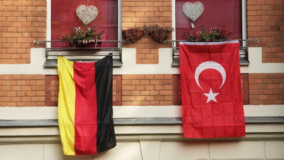 Eine rote, türkische Fahne mit dem Halbmond und dem Stern hängt während der Fußball-EM 2016 am 14.06.2016 in Berlin an einem Haus neben der deutschen Flagge in Schwarz-Rot-Gold. © picture alliance Foto: Wolfram Steinberg