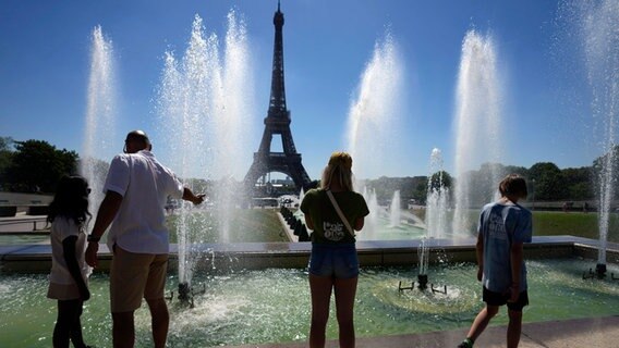 Der Eiffelturm, davor Menschen an einer Wasserfontäne im Hochsommer in Paris an der Seine © Francois Mori/AP/dpa +++ dpa-Bildfunk +++ Foto: Francois Mori