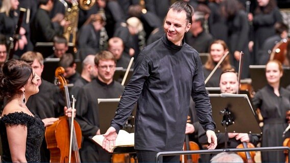 Il direttore d'orchestra Theodor Krentzis in una camicia nera guida la musica 