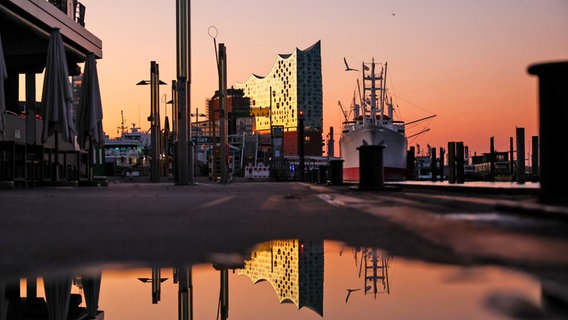 Die Elbphilharmonie beleuchtet im Abendrot am Hamburger Hafen, danaben das Schiff Cap San Diego und kreisende Möwen © Christian Charisius/dpa +++ dpa-Bildfunk +++ Foto: Christian Charisius