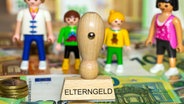 Spielfiguren und ein Stempel auf dem das Wort Elterngeld steht © imago 