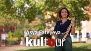 Die Saxophonistin Asya Fateyeva steht mit ihrem Instrument in einem Park und lächelt in die Kamera. © NDR 