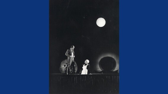 Schwarzweißbild von Peer Jäger als dritter Faust neben Marianne Barth vor einem großen Mond  