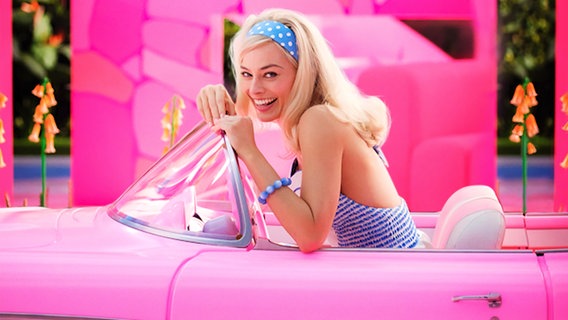 Margot Robbie in einem pinken Auto als Barbie im Film "Barbie" von Greta Gerwig © 2022 Warner Bros. Entertainment Inc. Foto: Jaap Buitendijk