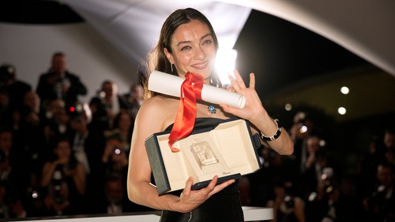 Die türkische Schauspielerin Merve Dizdar hält ihre Goldene Palme als Beste Schauspielerin hoch in Cannes 2023 © Daniel Cole/AP +++ dpa-Bildfunk Foto: Daniel Cole