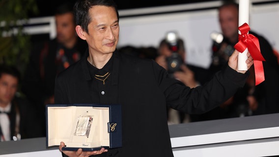 Tran Anh Hung, vietnamesisch-französische Regisseur, hält die Palme als bester Regisseur für Pot-au-Feu hoch beim Festival Cannes 2023 © Vianney Le Caer/Invision/AP/dpa +++ dpa-Bildfunk Foto: Vianney Le Caer