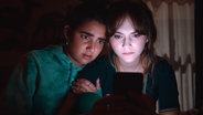Zwei junge Frauen starren voller Angst auf einen Smartphone-Bildschirm - Geraldine Viswanathan und Emilia Jones in "Cat Person" © Studio Canal GmbH 