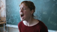 Leonie Benish screams as teacher Carla Nowak in the feature film "teacher's room" In front of a painting © Alamode Photo: Judith Kaufman