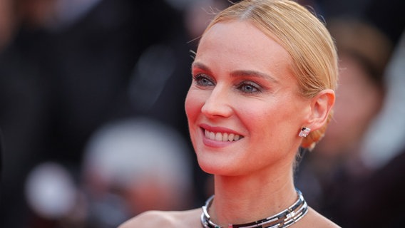 Schauspielerin Diane Kruger auf dem roten Teppich, man sieht ihr Gesicht und die Haare sind blond und zu einem strengen Zopf zurückgebunden. Sie lächelt. © abaca | Shootpix/ABACA Foto: Shootpix/ABACA