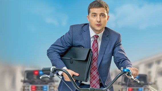 Szene aus der ukrainischen Serie "Diener des Volkes" mit Wolodymyr Selenskyj auf dem Fahrrad als Lehrer, der zum Präsidenten des Landes gewählt wird © eccho Rights 