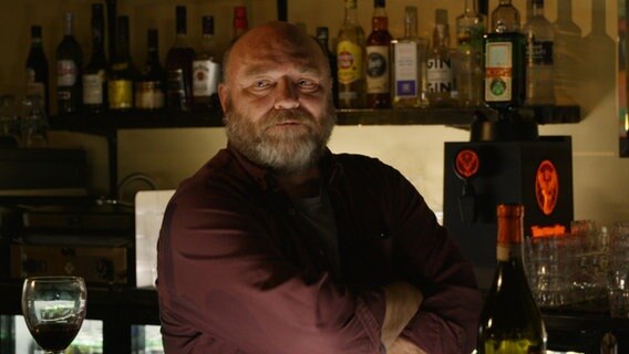 Ein etwa 50jähriger Mann mit Bart hinter einem Tresen in einer düsteren Bar (Szene aus Mika Kaurismäkis "Eine Nacht in Helsinki") © Mika Kaurismäki/ Arsenal Filmverleih 