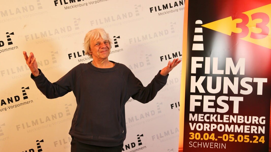 Der Filmemacher Andreas Dresen steht vor einer Plakatwand des Filmkunstfestes Mecklenburg-Vorpommern.