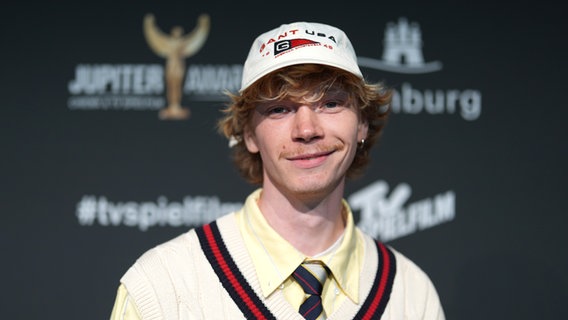 Ein junger Mann mit blonden Haaren und Käppi schaut fröhlich - Filip Schnack bei einer Hamburger Filmpremiere © picture alliance/dpa 
