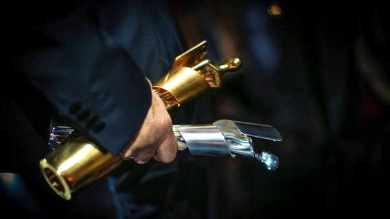 Eine Hand hält zwei Filmpreise. © IMAGO / Eventpress 