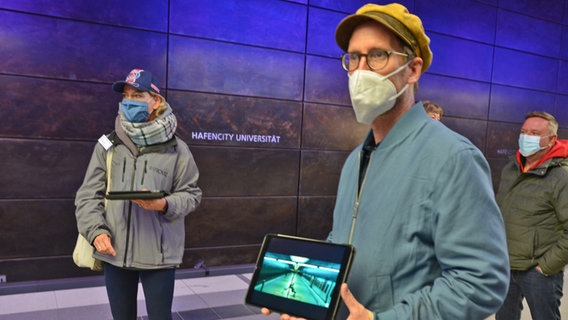 Der Historiker Arne Krasting (r.) zeigt auf einer Tour mit Tablets in der Hafencity Hamburgs berühmte Drehorte und die dazu gehörigen Filmgeschichten Der Historiker Arne Krasting (r.) zeigt auf einer Tour mit Tablets in der Hafencity Hamburgs berühmte Drehorte und die dazu gehörigen Filmgeschichten © NDR Foto: Patricia Batlle