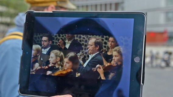 Auf einem Tablet ist eine Filmszene aus Ilker Cataks Liebesfilm "Es gilt das gesprochene Wort" zu erkennen, der in einer langen Szene in der Elbphilharmonie spielt © NDR Foto: Patricia Batlle