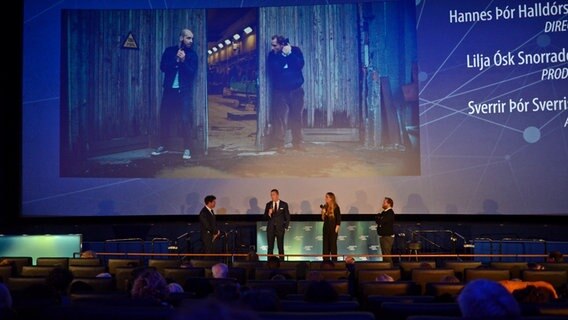 Das Team von "Cop Secret" mit Hannes Thór Halldórson vor Publikum im Saal bei der Eröffnung der Nordischen Filmtage Lübeck 2021 © NDR Foto: Patricia Batlle