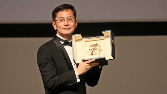 Ein Mann im Smoking und Brille hält eine Goldene Ehrenpalme des Filmfests Cannes hoch - Goyo Miyazaki, Sohn des Gründers des japanischen Animestudios Ghibli © picture alliance/dpa/MAXPPP MAXPPP PHOTOPQR/NICE MATIN/Patrice Lapoirie Foto: Patrice Lapoirie