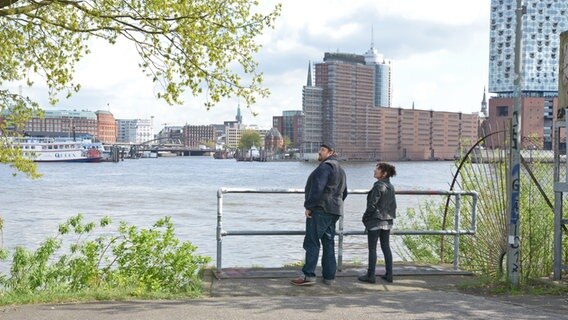 Zwei Personen an der Elbe, im Hintergrund der Hafen von Hamburg - Dreharbeiten am Hafen zum Spielfilm "Triage" der Serie "Großstadtrevier" mit Maria Ketikidou in Hamburg © NDR Foto: Patricia Batlle