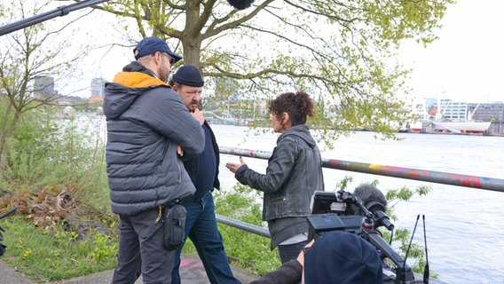 Mehrere Menschen besprechen sich am Ufer der Elbe bei Dreharbeiten zum Spielfilm "Triage" der Serie "Großstadtrevier" mit Maria Ketikidou in Hamburg © NDR Foto: Patricia Batlle