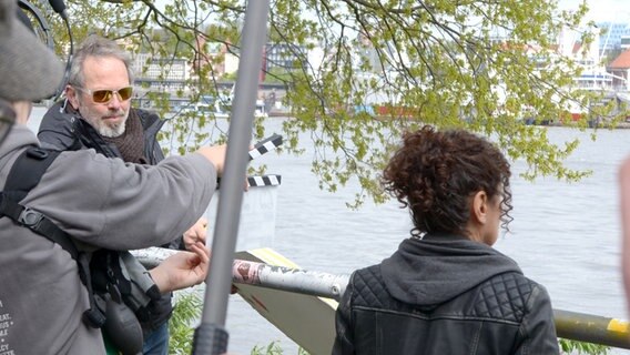 Eine Klappe beim Dreh vor einer Frau mit Pferdeschwanz - Dreharbeiten am Hafen zum Spielfilm "Triage" der Serie "Großstadtrevier" © NDR Foto: Patricia Batlle