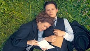Zwei Menschen lliegen im Gras, die Frau liest dem Mann aus einem Brief vor - Milena Jesenska (Liv Lisa Fries) und Franz Kafka (Joel Basman, v.l.n.r.) in der ARD-Serie "Kafka" © NDR/Superfilm 