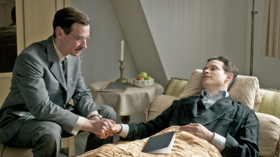 David Kross (links) spielt Max Brod, Joel Basman Franz Kafka, der sterbend im Bett liegt, in der ARD/ORF-Serie "Kafka" © NDR/Superfilm 