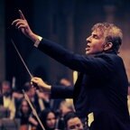 Bradley Cooper spielt Leonard Bernstein beim Dirigieren eines Orchesters mit erhobenem Arm im Film "Maestro" © Jason McDonald Netflix 2023 Foto: Jason McDonald
