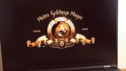 Ein Laptop zeigt eine Ansicht vom Logo der "MGM"- Metro Goldwyn Meyer mit dem fauchenden Löwen © IMAGO / Pond5 Images 