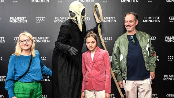 Redakteurin Sabine Holtgreve, Schauspielerin Hannah Schiller und Regisseur Alexander Adolph mit einer Fantasy-Figur mit Kopf eines Geiers bei  der Premiere von der Serie "Die nettesten Menschen der Welt" auf dem Filmfest München © Filmfest München / Ronny Heine Foto: Ronny Heine