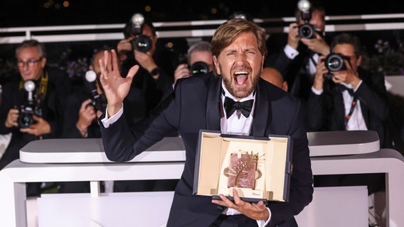 Ruben Östlund freut sich mit seiner Goldenen Palme für "Triangle of Sadness" in Cannes. © Vianney Le Caer/Invision/AP/dpa +++ dpa-Bildfunk +++ Foto: Vianney Le Caer