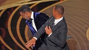 Will Smith (r.) ohrfeigt Chris Rock auf der Bühne bei der Oscar-Preisverleihung 2022 in Los Angeles ©  Chris Pizzello/Invision/AP/dpa +++ dpa-Bildfunk +++ Foto:  Chris Pizzello