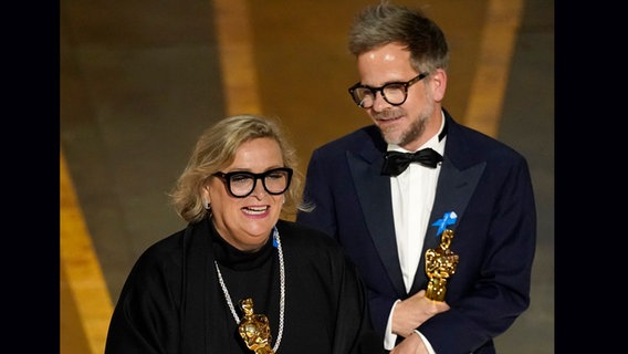 Ernestine Hipper (links) und Christian M. Goldbeck mit ihren Oscars fürs beste Produktionsdesign von "Im Westen nichts Neues" bei der Oscar-Preisverlehung in Hollywood. © dpa bildfunk/Invision/AP Foto: Chris Pizello