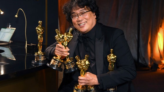 Der südkoreanische Regisseur und Autor Bong Joon Ho hält in Los Angeles die vielen Oscars für seinen Film "Parasite" im Arm - unter anderem die für den "besten Film" © Richard Shotwell/ /Invision / AP/ dpa bildfunk Foto: Richard Shotwell