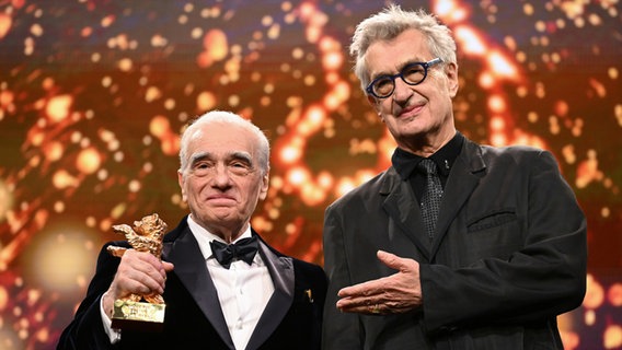 US-Regisseur und Autor Martin Scorsese (links) hält den Goldenen Ehrenbären in der Hand, daneben steht der deutsche Regisseur Wim Wenders, beide in dunklen Anzügen gekleidet © Sebastian Christoph Gollnow/dpa +++ dpa-Bildfunk +++ Foto: Sebastian Christoph Gollnow