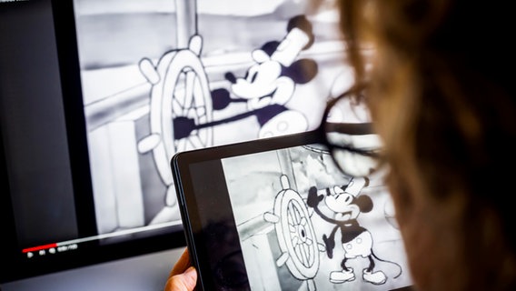 Eine Person schaut auf einem Tablet den Cartoon "Steamboat Willie" - die früheste Cartoon-Version von Micky Mouse © picture alliance / Sipa USA | Richard B. Levine Foto: Richard B. Levine